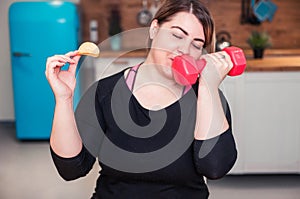 Sport with unhealthy food. combination of active life with fast food. close up photo. fat woman choosing dumbbell not hamburger