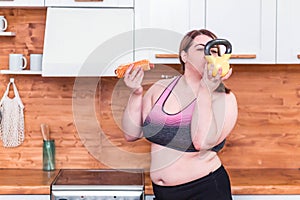 Sport with unhealthy food. combination of active life with fast food. close up photo. fat woman choosing kettlebell not hamburger