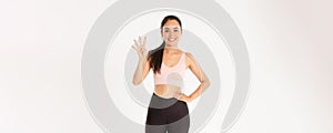 Sport, wellbeing and active lifestyle concept. Smiling cute brunette asian athlete, fitness girl showing four fingers