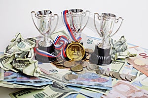 Sport winning concept: three cups among diverse currencies euro, dollar, rubl, gold medal first place
