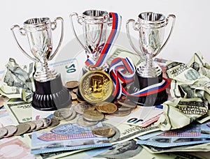 Sport winning concept: three cups among diverse currencies euro, dollar, rubl, gold medal first place