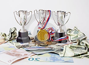 Sport winning concept: three cups among diverse currencies euro, dollar, rubl, gold medal first place close up