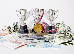 Sport winning concept: three cups among diverse currencies euro, dollar, rubl, gold medal first place close up