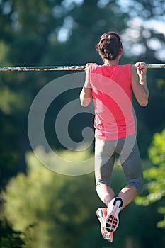 Sport woman athlete is Chin-ups and Pullups training on an abandoned sports field. Pull-up on the bar. Athlete Outdoors.