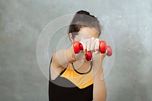 Sport woman beats hand with dumbbells to camera