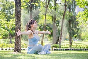 Sport woman breathing deeply fresh air with arms raised outdoor in park