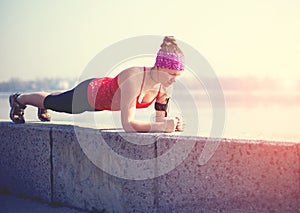 Sport woman doing plank outside in city quay