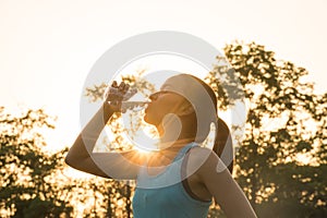 Sport woman drinking water during morning jogging