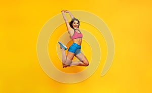 Sport woman jumps on a yellow background. Happy and joyful expression.