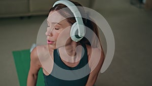 Sport woman listening music in headphones at workout close up. Girl stretching