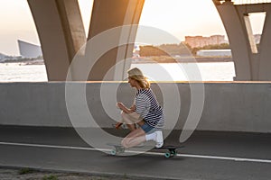 Sport woman making tricks on longboard riding skateboard for relaxation or active hobby at sunset