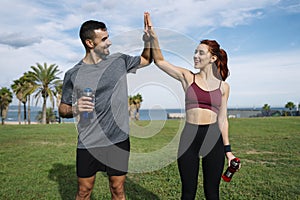 Sport woman and a man high five after a running outside workout. Fitness couple celebrating after successful exercising