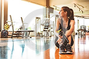 Sport woman relax resting after workout or exercise in fitness gym. Sitting and drinking protein shake or drinking water on floor