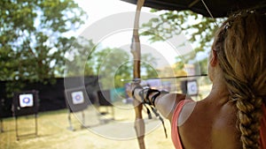 Sport woman in shooting range with bow. Athlete keep wooden bow. Sportsman in shooting gallery aim an arrow to hit