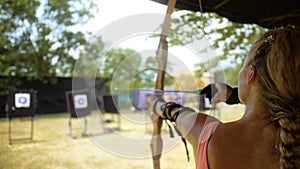 Sport woman in shooting range with bow. Athlete keep wooden bow. Sportsman in shooting gallery aim an arrow to hit