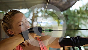 Sport woman in shooting range with bow. Outdoor archery training. Practice and training of archery in shooting range