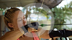 Sport woman in shooting range with bow. Outdoor archery training. Practice and training of archery in shooting range