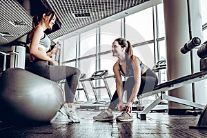 Sport woman sitting and resting after workout or exercise in fitness gym.