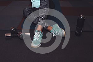 Sport woman sitting and resting after workout or exercise in fitness gym with protein shake or drinking water on floor