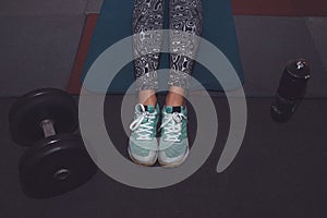 Sport woman sitting and resting after workout or exercise in fitness gym with protein shake or drinking water on floor