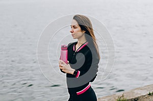 Sport woman sitting and resting after workout or exercise in fitness gym with protein shake or drinking water on floor. Relax