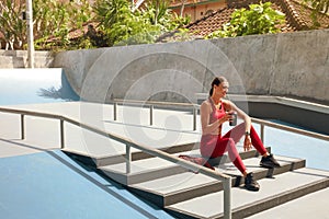 Sport. Woman On Stairs With Bottle Of Protein Shake Having Break. Sporty Girl In Fashion Sportswear Sitting Outdoor.