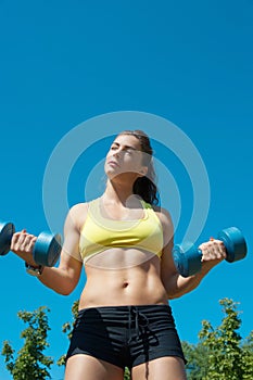 Sport woman stretching with dumbbells on playground