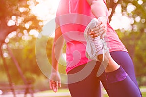 Sport woman stretching leg muscle preparing for running in the public park outdoor. Close up of female athlete lower body doing