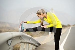 Sport woman stretching leg muscle after running workout on asphalt road with dry desert landscape in hard fitness training session