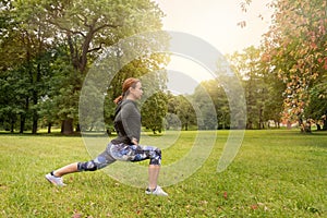 Sport woman wearing exercise suit doing stretching fitness exercise in city park at green grass