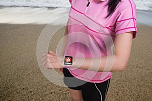 Sport woman wearing smartwatch with health sensor on beach background