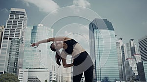 Sport woman wearing wireless headphones and stretching muscles before running in city, warmup exercise