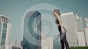 Sport woman wearing wireless headphones and stretching muscles before running in city, warmup exercise