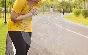 Sport womanman having heart attack or chest pain after running workout at park. Sport and Health care concept