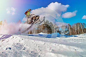 Sport yellow snowmobile jump. Cloud of snow dust from under snowmobile tracks. Concept quick movement. photo