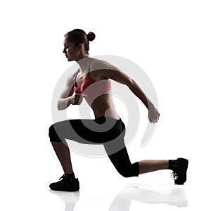 Sport young athletic woman doing lunge, silhouette studio shot o