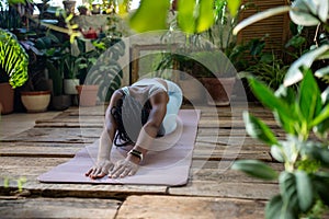 Sported black woman doing stretching exercise for back flexibility relaxation muscles on fitness mat