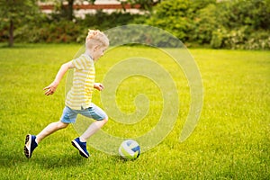 Sporting boy plays football in sunny park