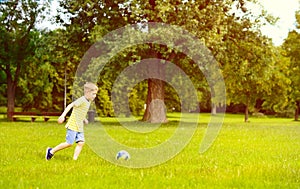 Sporting boy plays football in sunny park