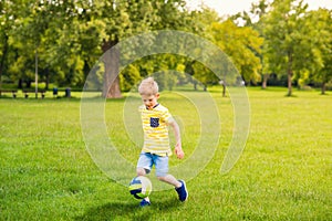 Sporting boy plays football in sunny park photo