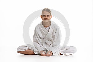 Sporting girl in keikogi sits on the floor, white background