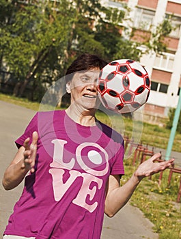 Sporting an old woman enthusiastically tries to catch ball thrown to her.Playing football.