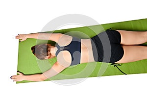 Sporting a tired young girl lies face down on a yoga mat on a white background.