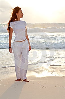 Sporting woman on the sea coast on a beach on a sunset.Portrait in a sunny day