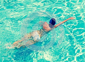 The sporting woman swims in bright blue water