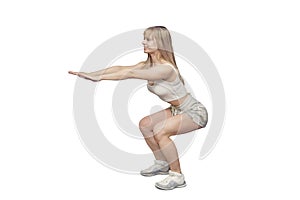 Sportive blonde gymnast in the sportswear squats on the white background in the studio. Shoot from the side. . She holds her hands