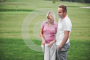 Sportive couple playing golf on a golf course, they stand to the next hole