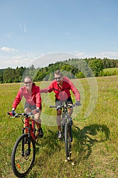 Sportive couple riding bike in summer meadow