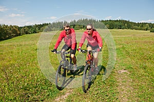 Sportive couple riding in summer meadow
