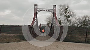 Sportive couple training outdoor. Brunette female and male are jogging on bridge across river in park. Woman and man doing morning